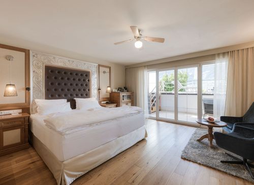 Helles Schlafzimmer der Luxury Suite Lantana mit großem Bett, Sitzbereich und Zugang zum Balkon.