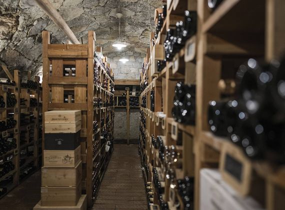 File di bottiglie di vino sono disposte su scaffali in legno in una cantina con pareti in pietra a Preidlhof.
