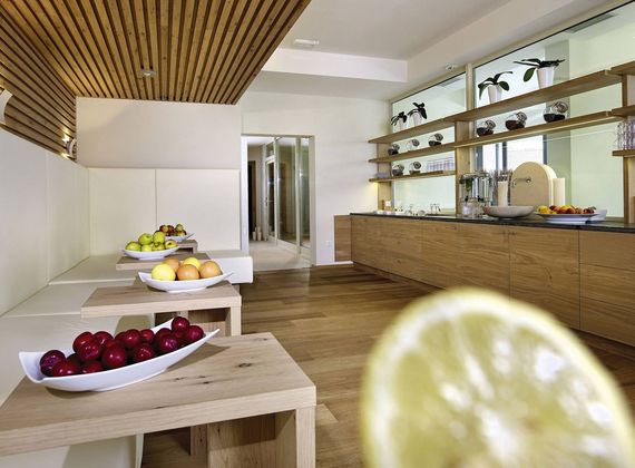 Ein heller Ruheraum im Wellnessbereich mit Holzmöbeln und mehreren Schalen mit frischem Obst.